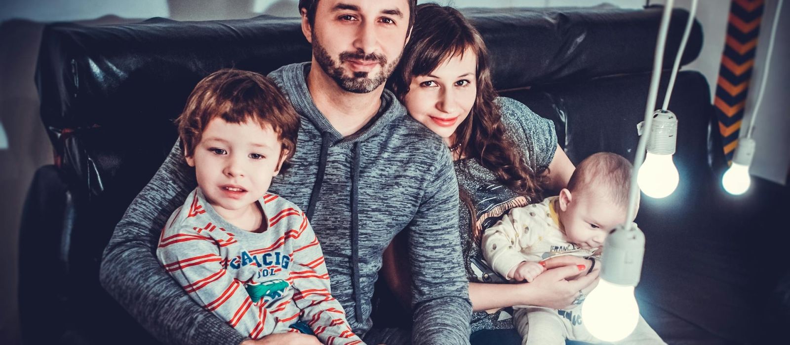 Gezin bestaande uit vader en moeder die elk een baby vasthouden in hun armen.