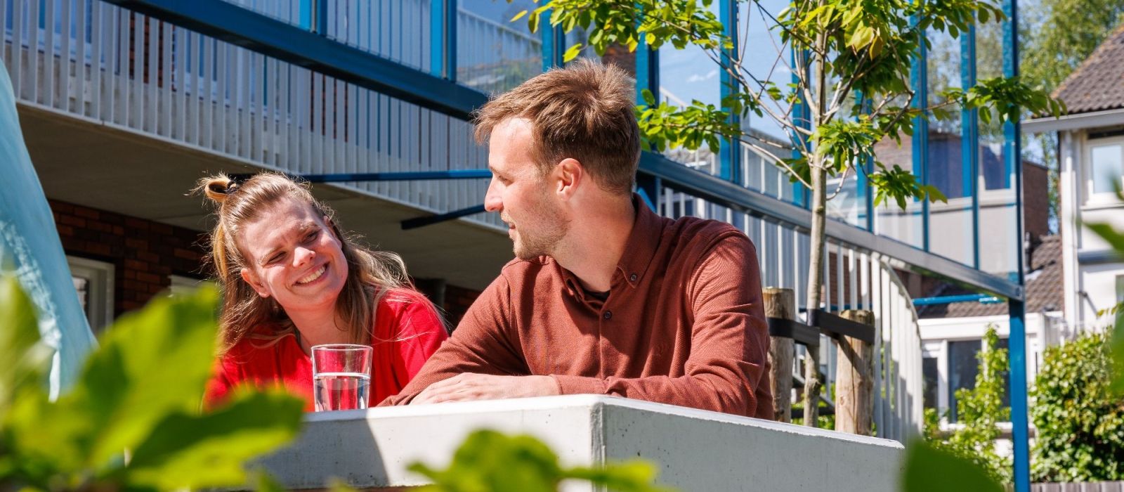 Een medewerker en een cliënt in de zon aan een tafel