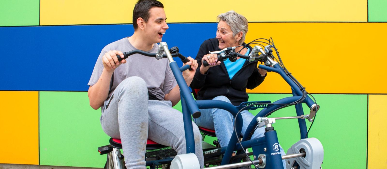 Een cliënt en een begeleider zitten op een duo-fiets