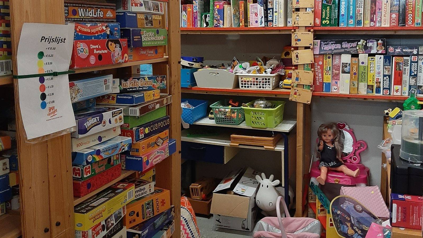 Spullen die in de schappen liggen van kringloopwinkel Gebruikt Goed