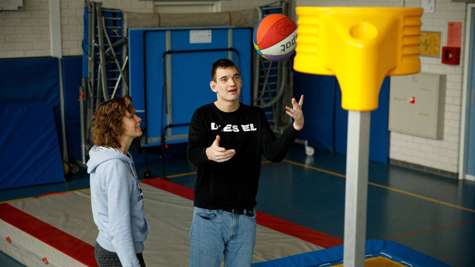 begeleider met cliënt aan het basketballen