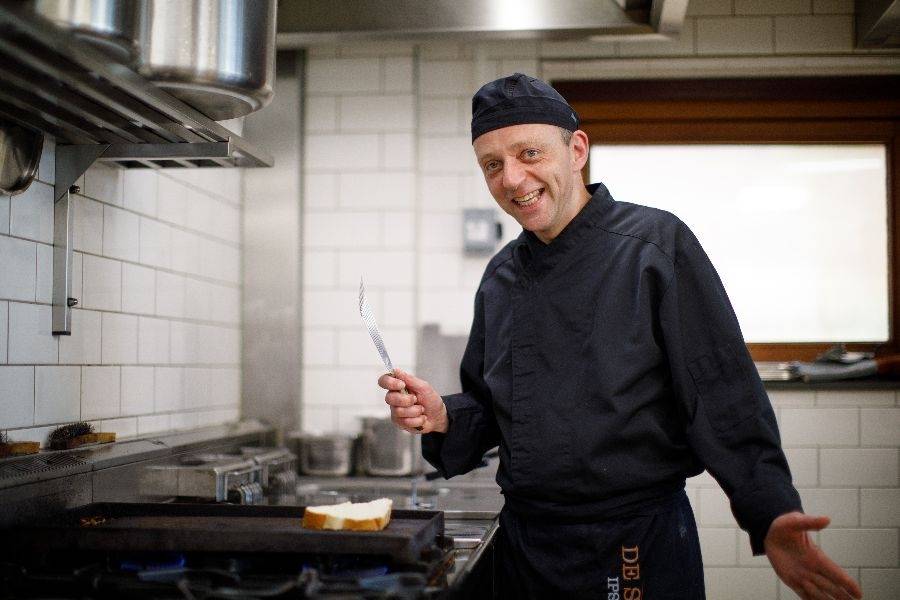 Vrolijke medewerker in de keuken van lunchcafé De Smulhoeve