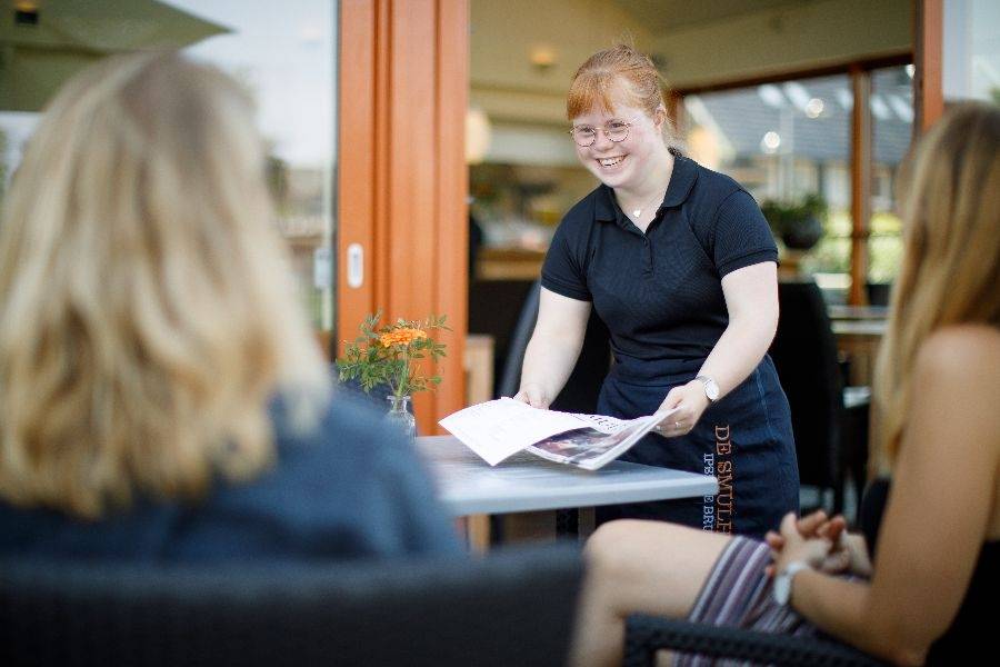 Medewerkster van lunchcafé De Smulhoeve serveert op het terras