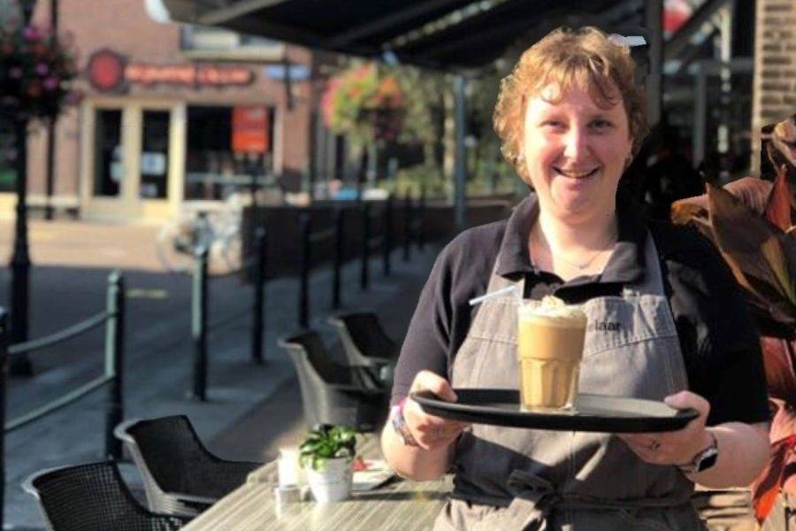 Medewerkster van lunchcafé De Zoetelaar serveert op het terras