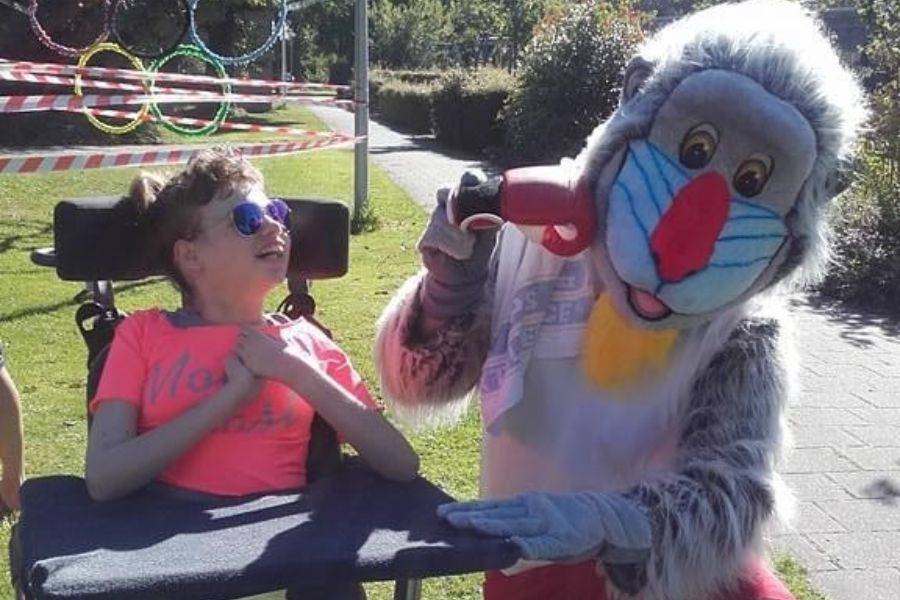 cliënt in rolstoel samen met mascotte MOEF tijdens olympische spelen